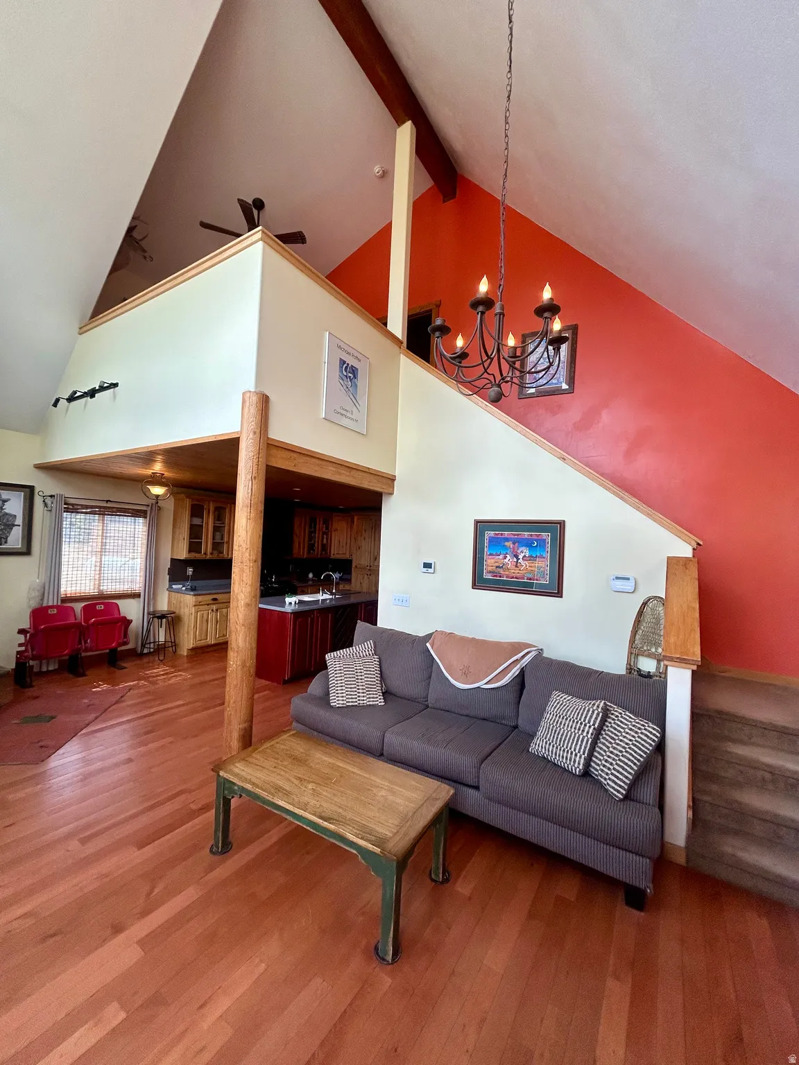 Spacious living area featuring wood-finish flooring, vaulted ceilings with exposed beams, and a lofted space
