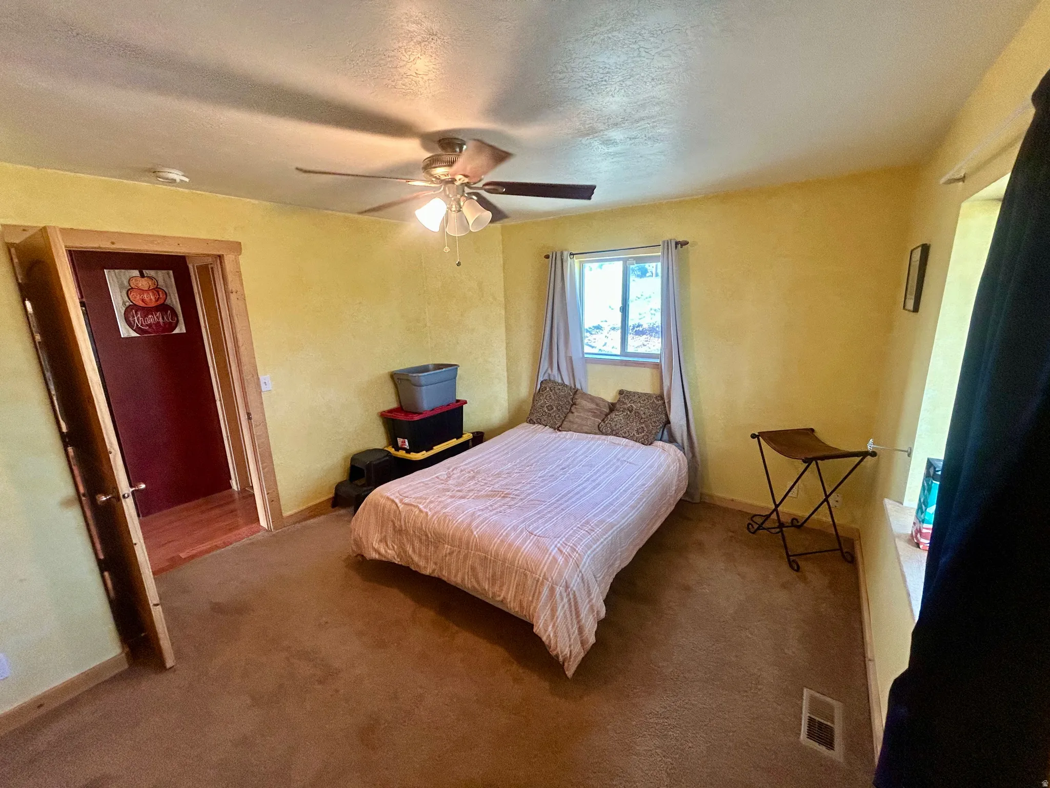 Carpeted room featuring a ceiling fan with integrated lighting, a window with a wood sill, and a contrasting wood-trimmed doorway