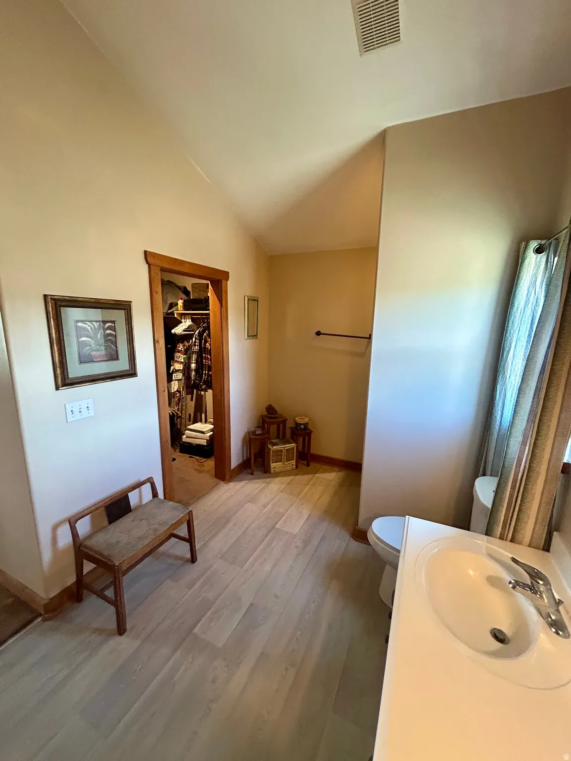 Primary Bathroom featuring a single vanity, wood-finish flooring, and natural wood door trim