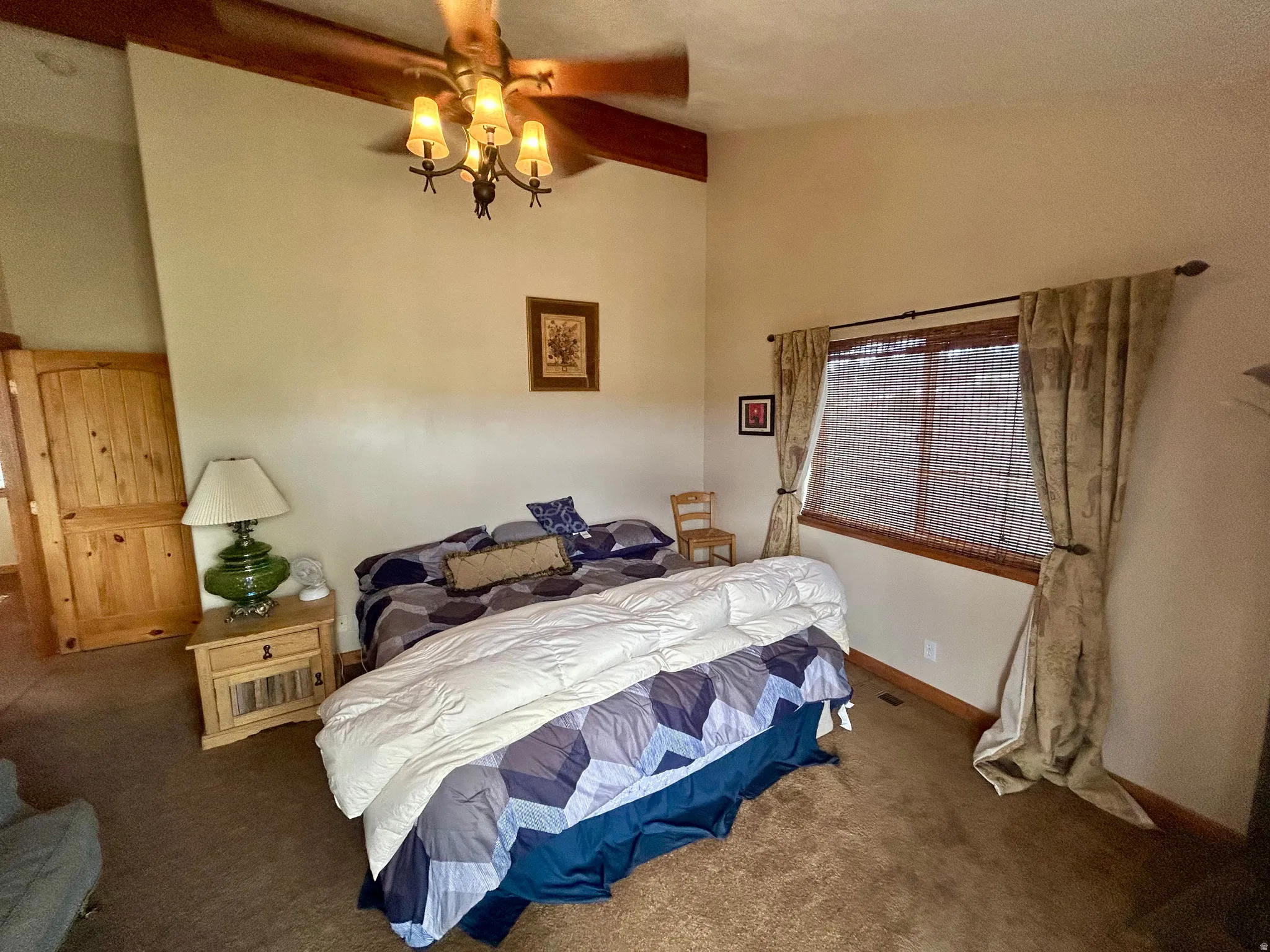 Primary Bedroom with vaulted ceiling featuring exposed wood beams and a ceiling fan with integrated lighting