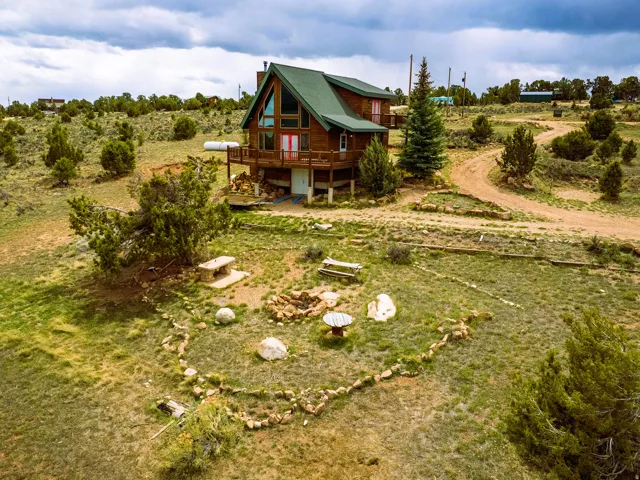 Rustic cabin exterior featuring a green roof and a raised wood deck