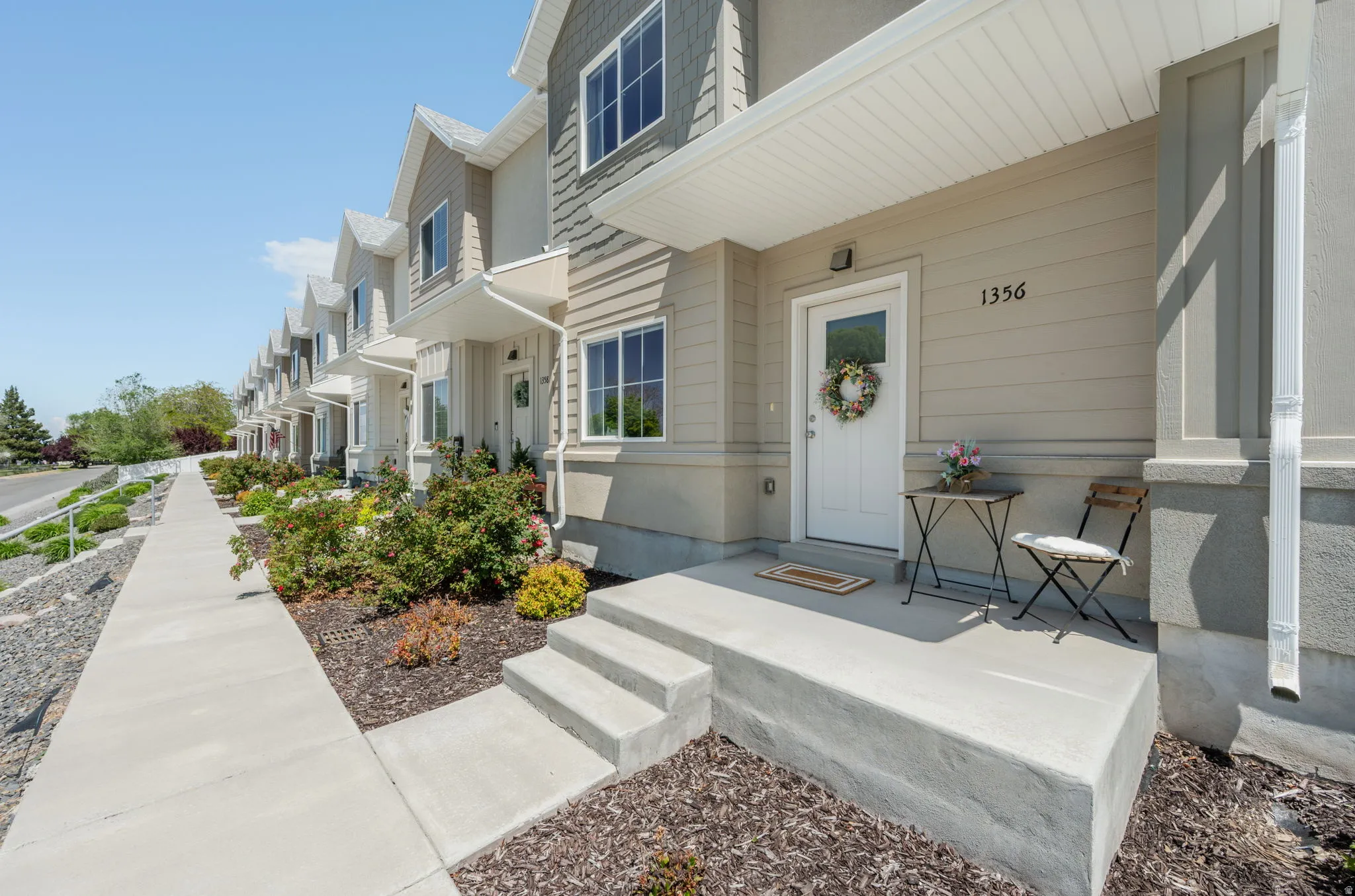 Exterior featuring light neutral siding, white trim, and a covered entry porch