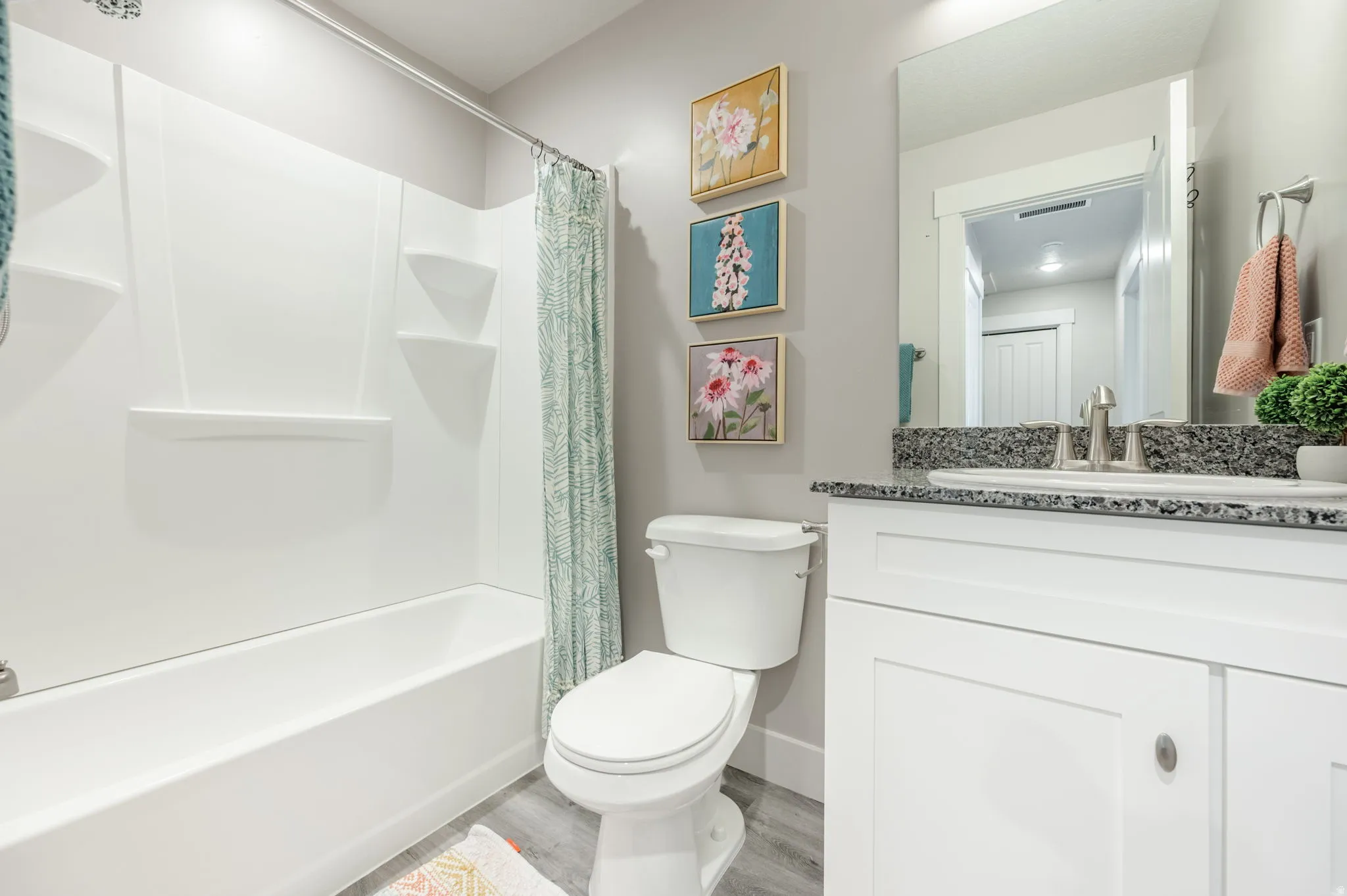 Bathroom featuring a white bathtub and shower surround, a toilet, and a vanity with a dark speckled countertop