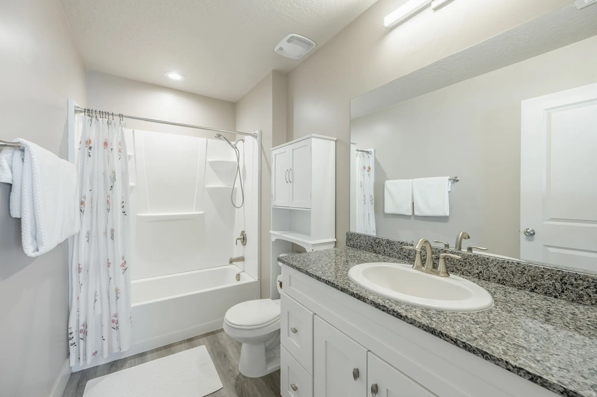 Bathroom featuring a vanity with a granite countertop, undermount sink, and brushed nickel faucet