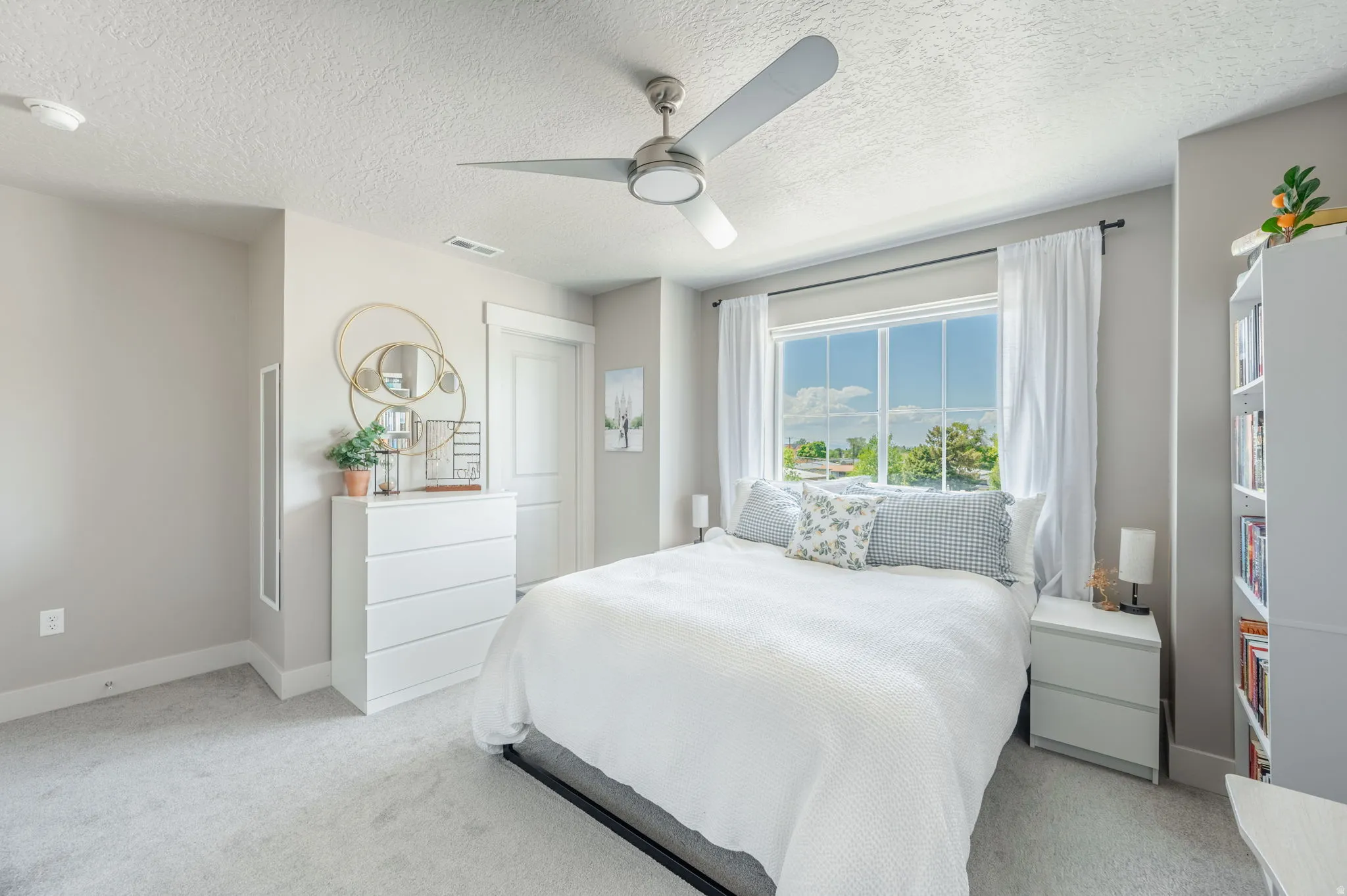 Bright room featuring a large multi-pane window, light-colored carpeting, and a ceiling fan with integrated lighting