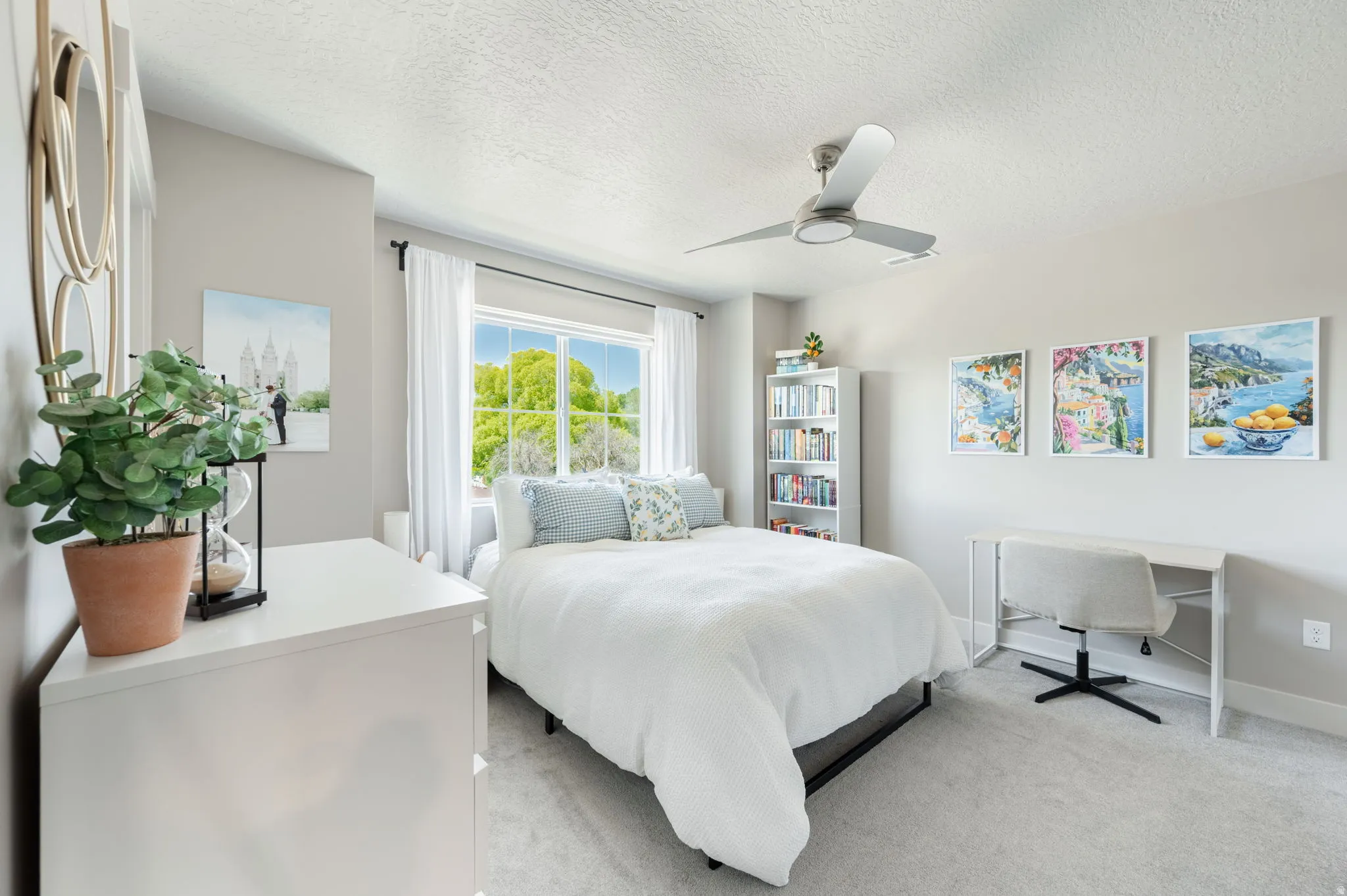 Bedroom featuring carpet flooring, a multi-pane window with white blinds and drapes, a ceiling fan, and a built-in shelving unit