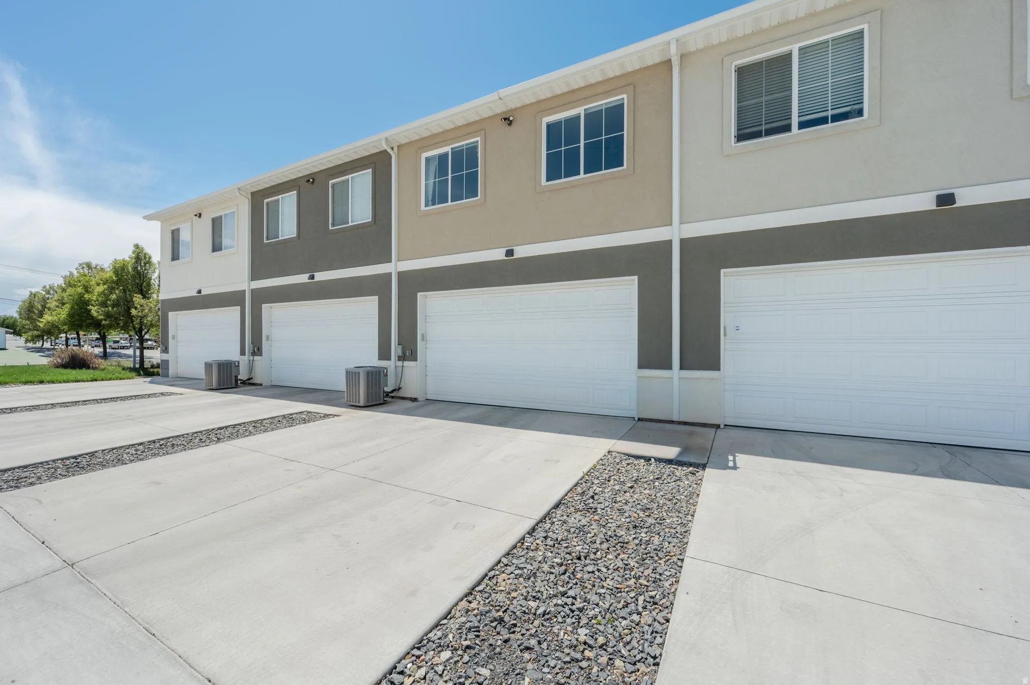Townhome exterior featuring individual garage access and a dedicated concrete parking pad