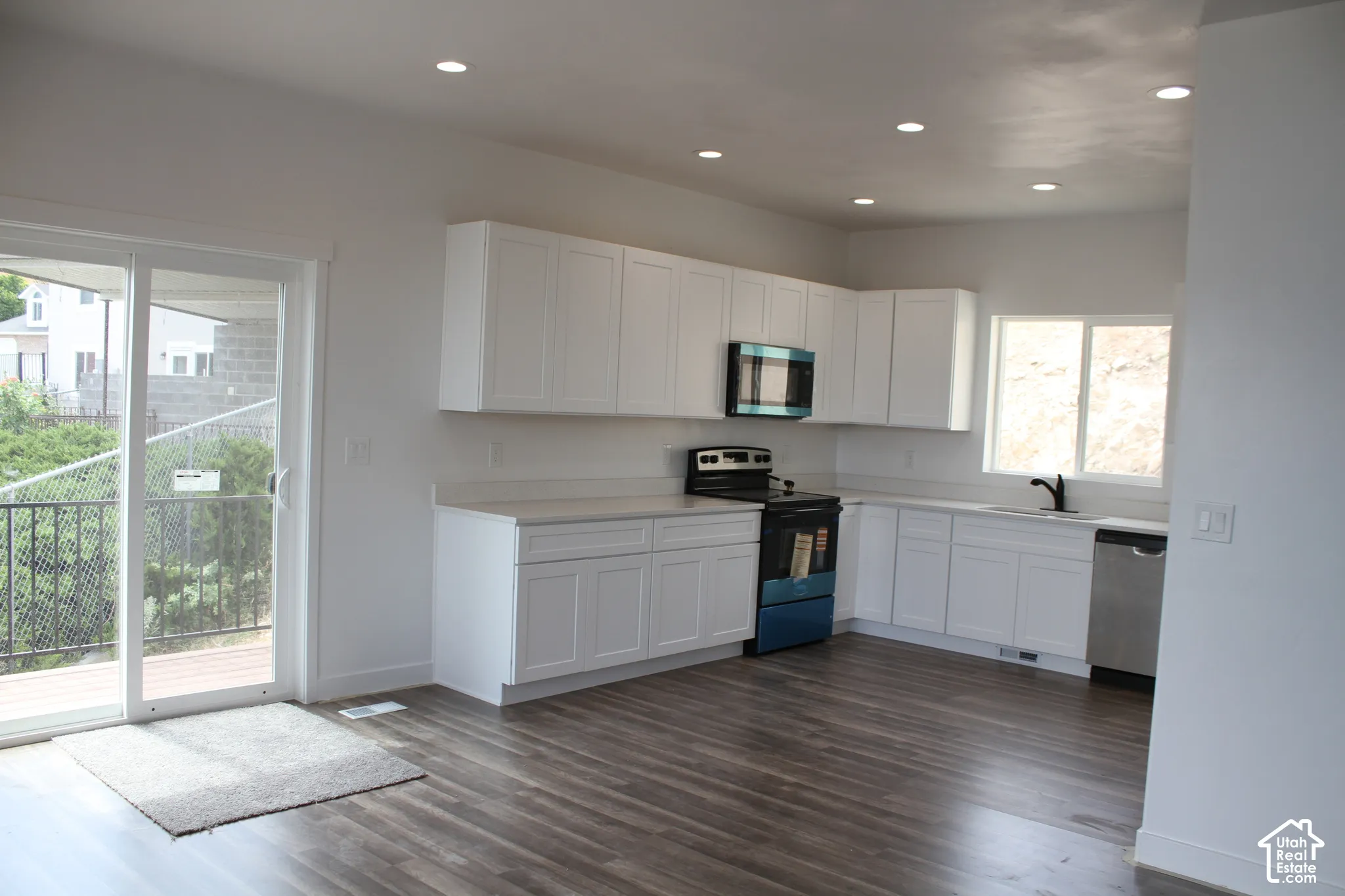 Contemporary kitchen featuring white shaker cabinetry and light-toned countertops