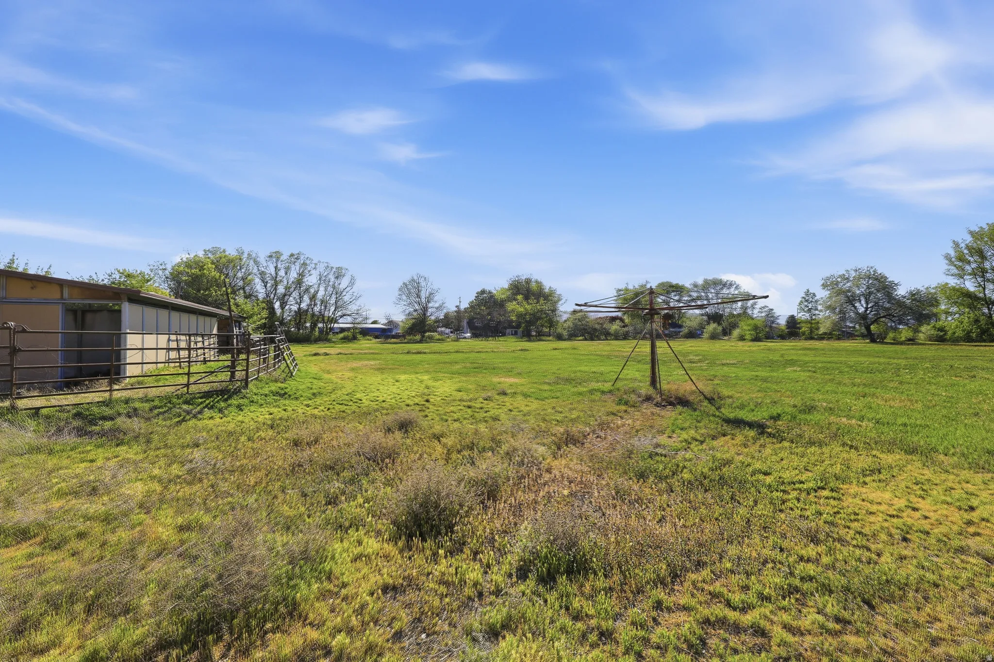 Expansive green field featuring a barn structure with an attached corral