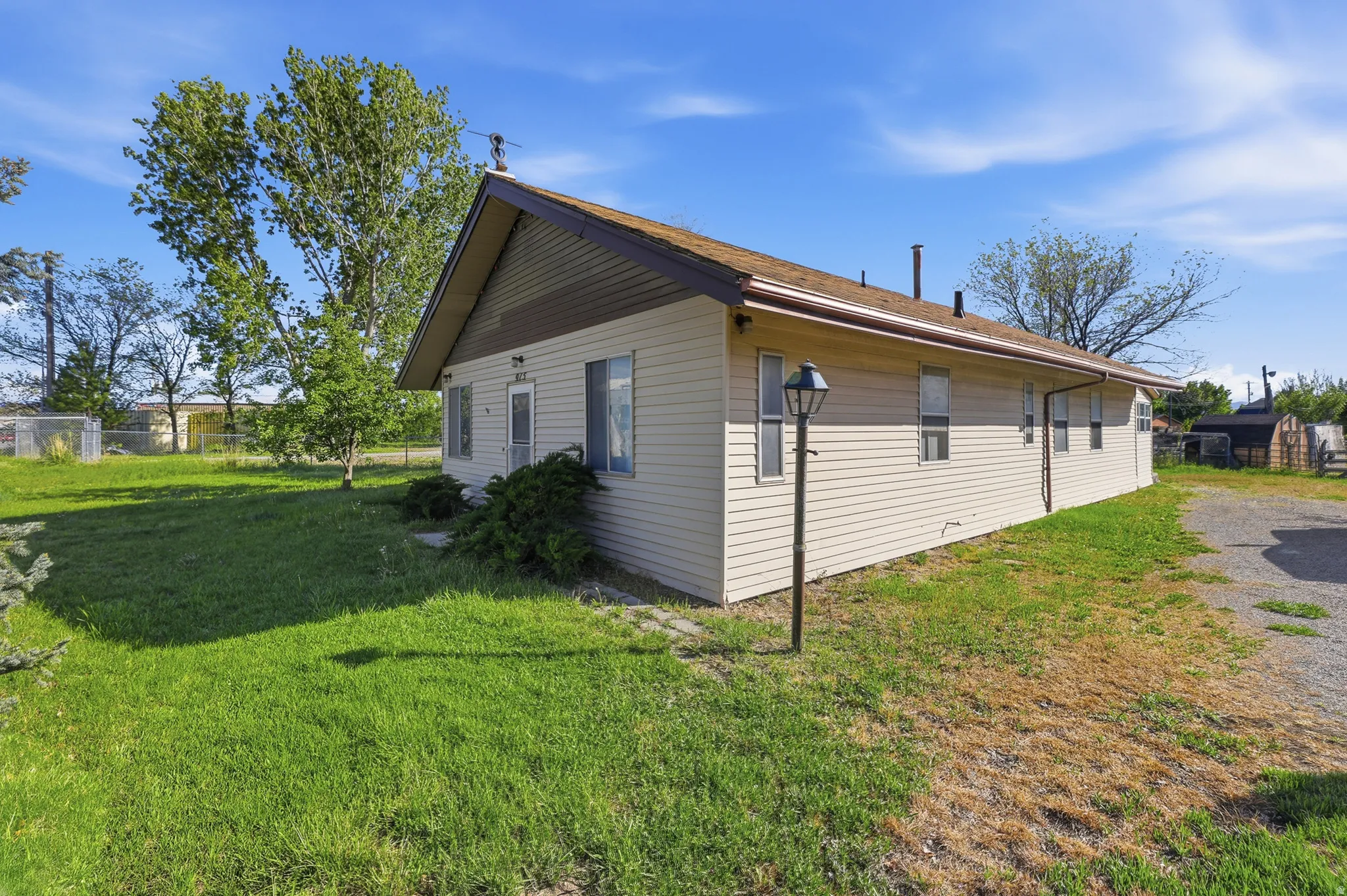 Single-story exterior with light-colored siding, a brown roof, and a prominent front gable