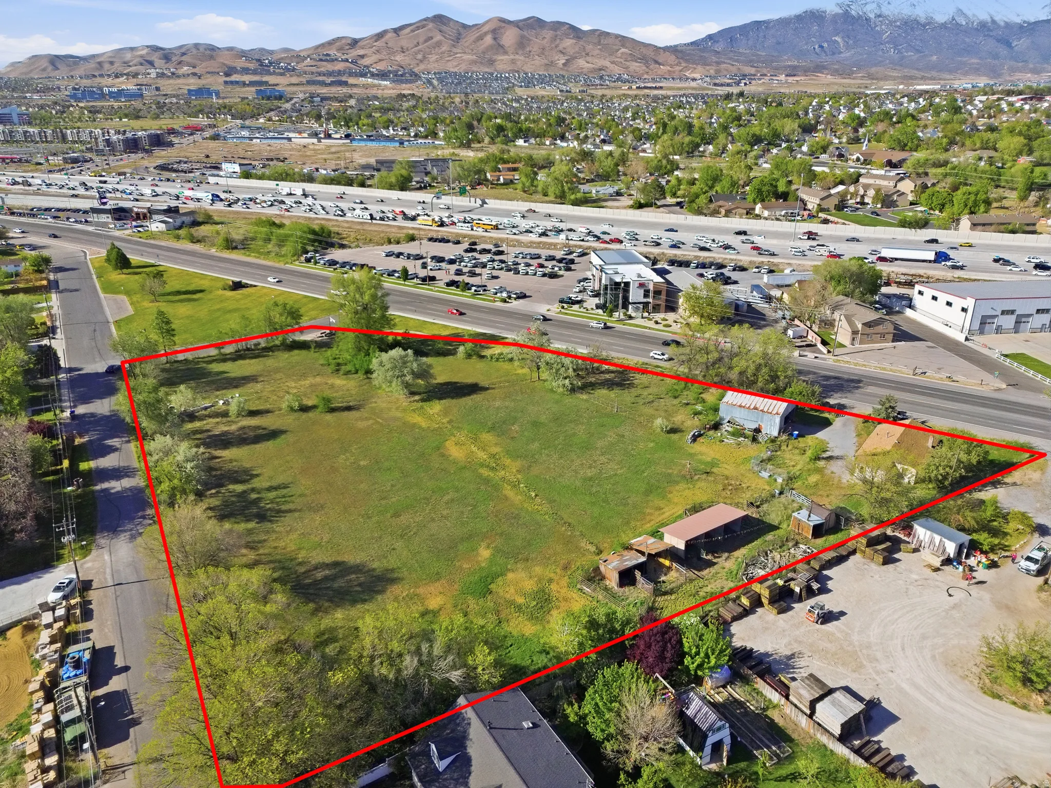 Expansive undeveloped land parcel featuring existing structures, direct road frontage, and mountainous scenery