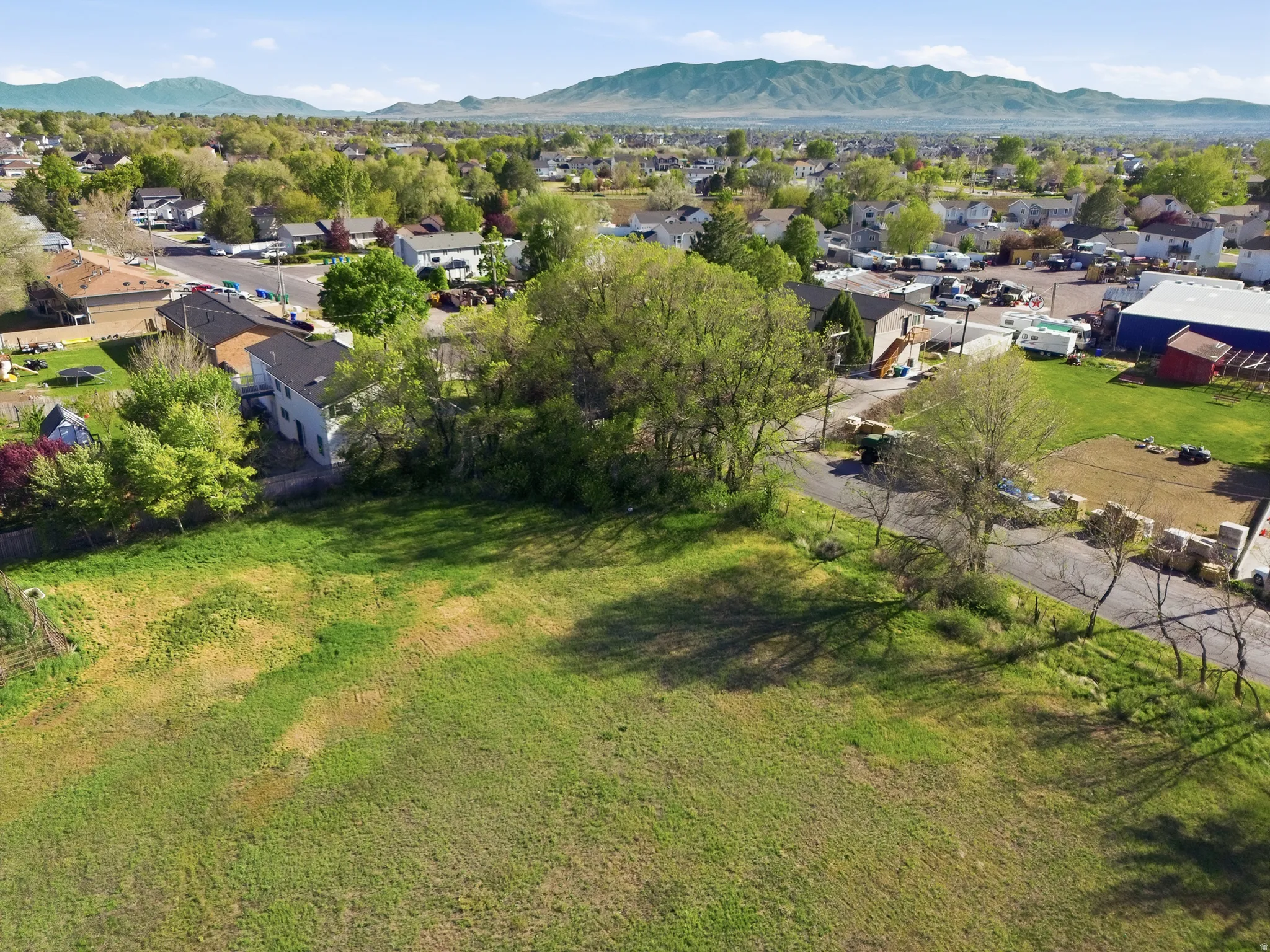 Expansive open land area with green grass and visible mountain backdrop