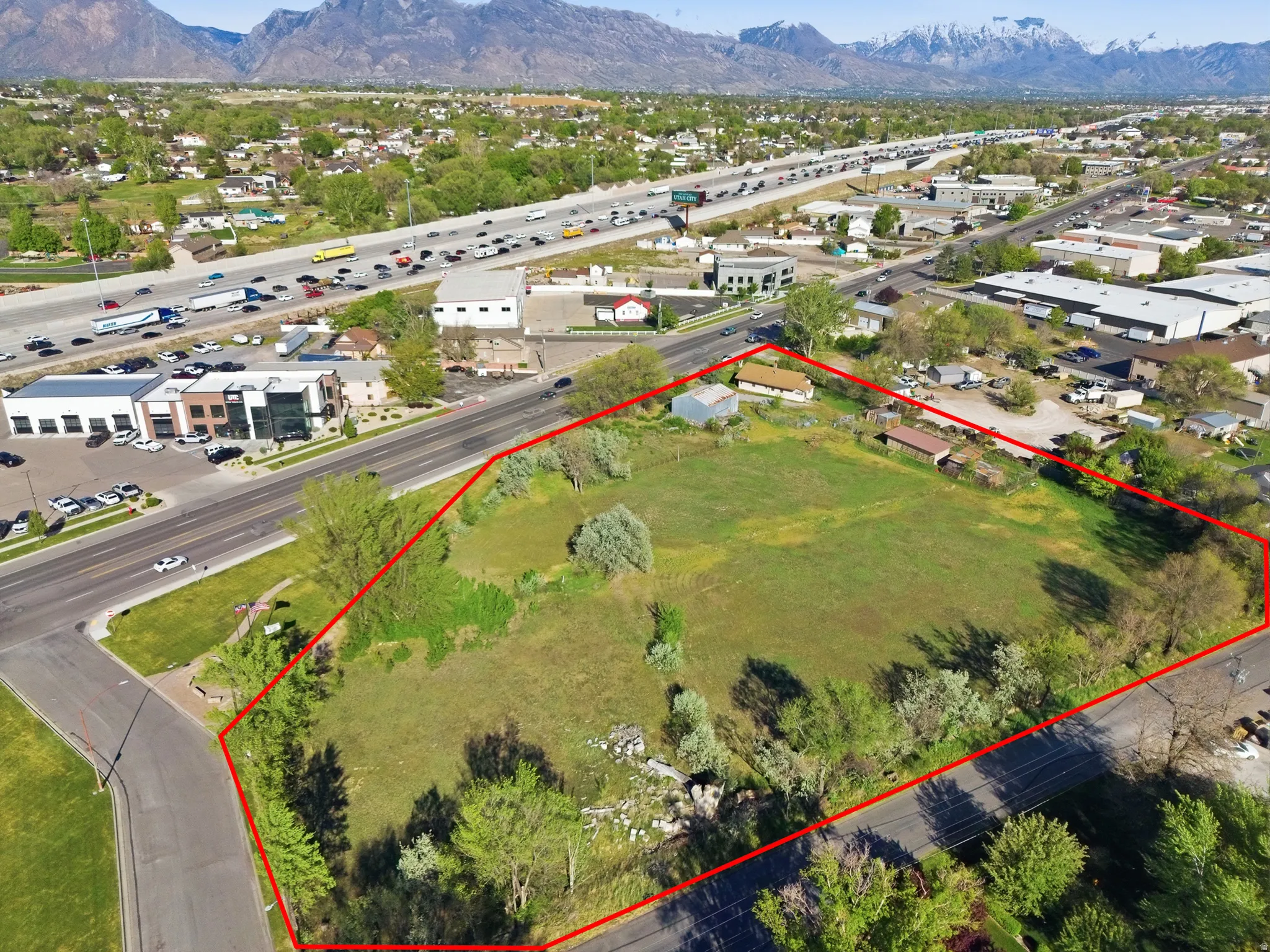 Expansive undeveloped lot featuring a large grassy area, mature trees, and a visible roadway