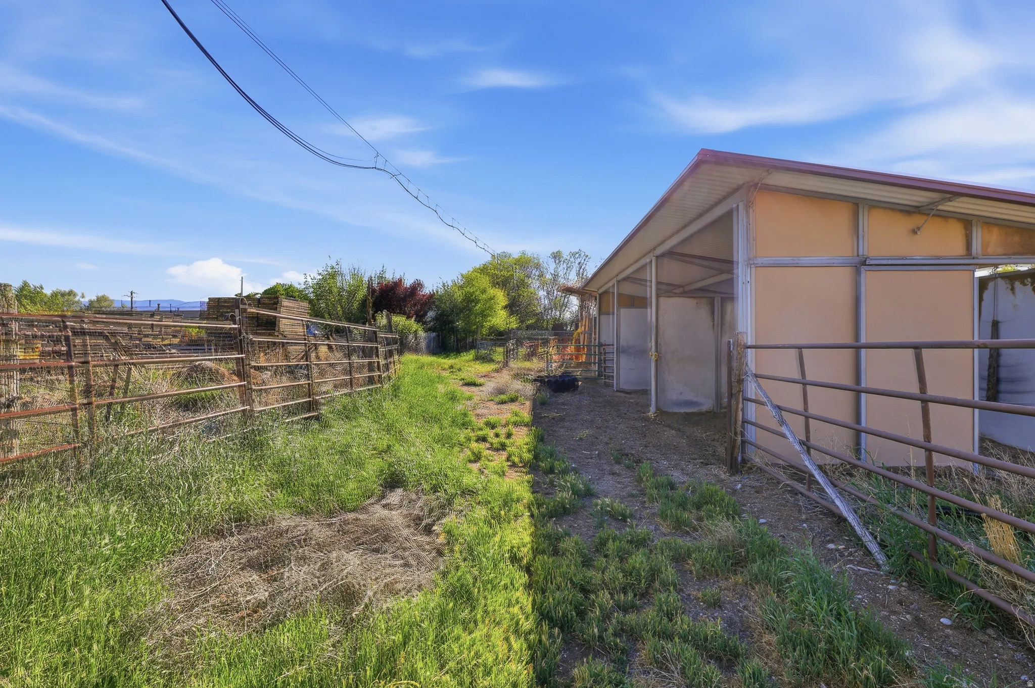 Sheltered outdoor structure featuring multiple open-stall bays and a sloped metal roof