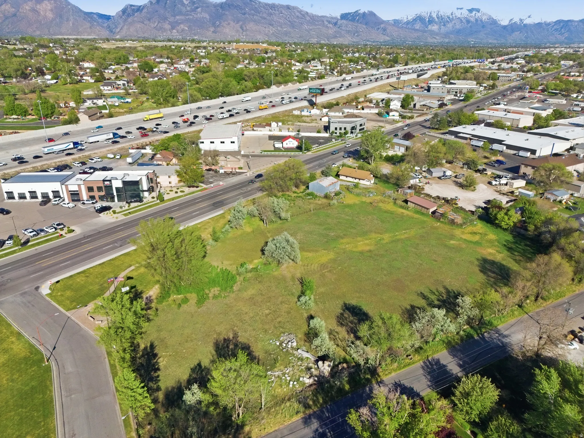 Expansive undeveloped parcel featuring a green grass surface and surrounding mature trees