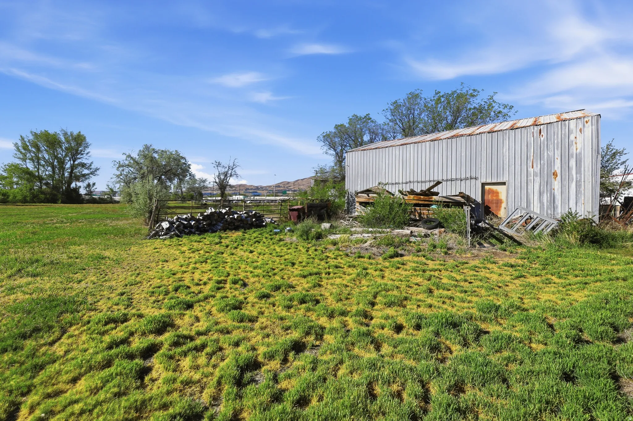 Corrugated metal outbuilding with a single entry door and an expansive grassy field foreground