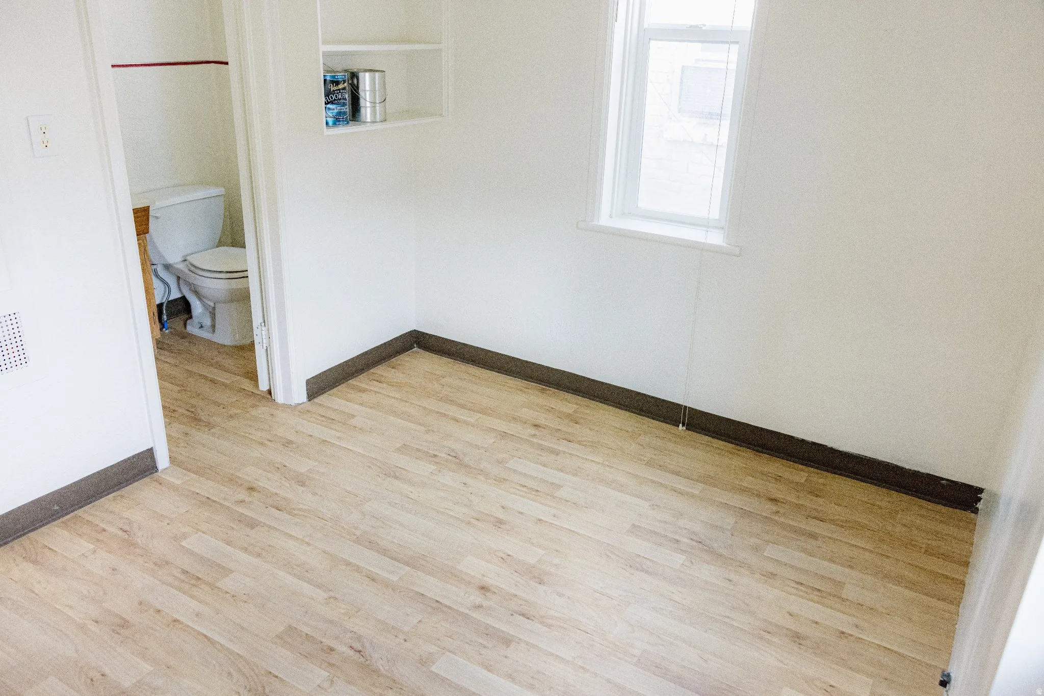 Room featuring wood-finish flooring, white walls, and dark baseboards