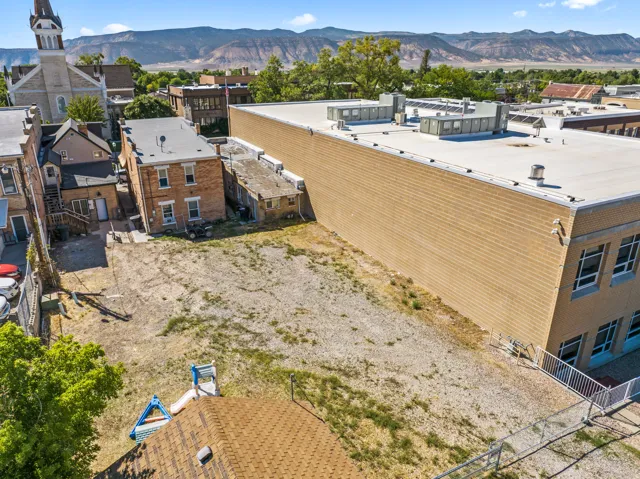 Expansive gravel lot offering significant development potential, flanked by a multi-story brick building and a larger commercial structure