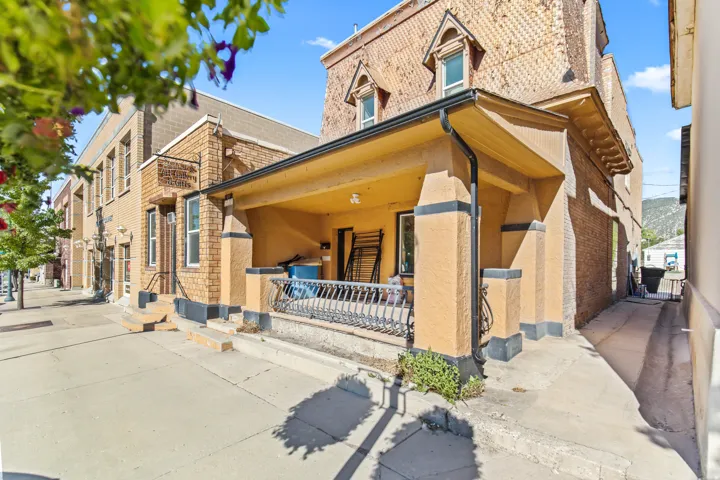 Exterior building featuring a covered porch with a decorative railing, brick facade, and multiple windows