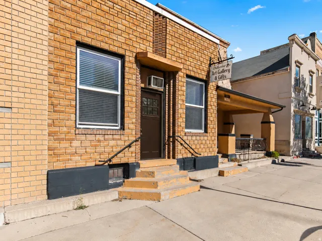 Brick exterior with a covered entryway, multiple windows, and a black handrail