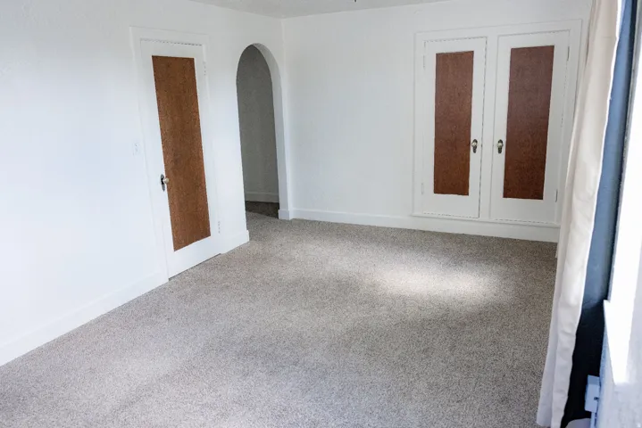 Spacious room featuring light-toned carpet flooring, white painted walls, and white trim