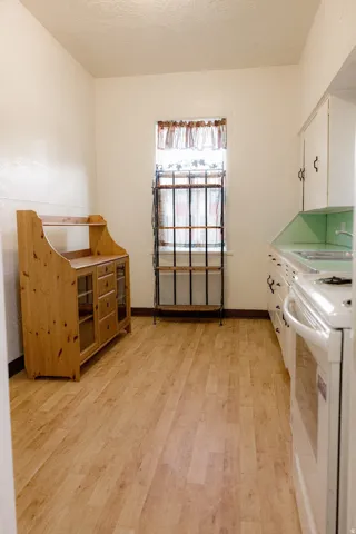 Kitchen featuring wood-finish flooring, white walls, and a window with security bars
