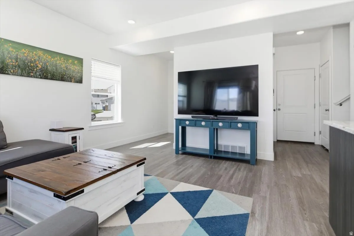 Open-concept living space featuring wood-finish flooring, recessed lighting, white trim, and a white interior door