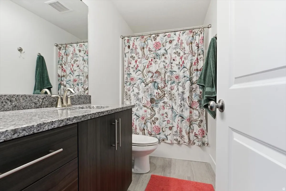 Bathroom featuring a dark wood-finish vanity with a granite countertop and undermount sink