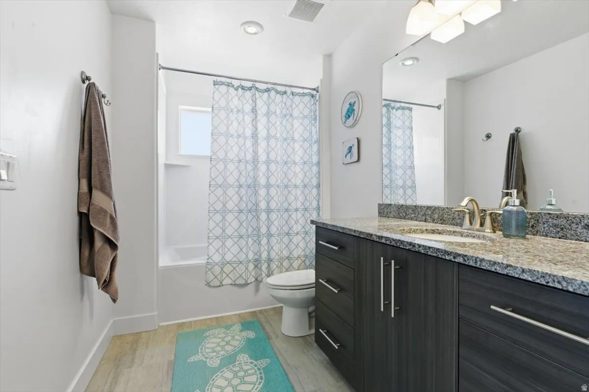 Bathroom featuring a dark wood-finish vanity with a light granite countertop, an undermount sink, and a chrome faucet