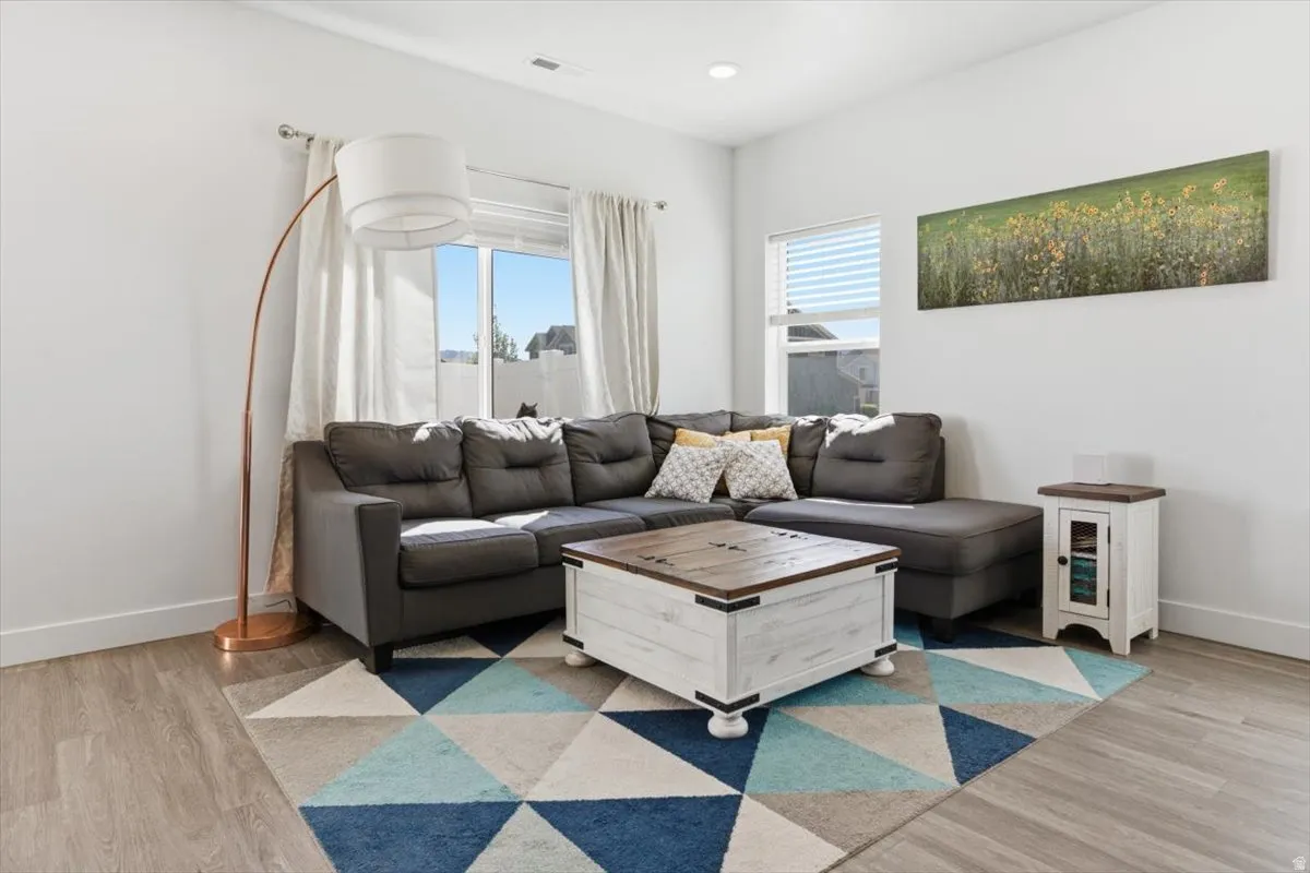 Living area featuring wood-finish flooring, recessed lighting, and white baseboards