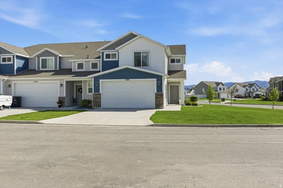 Modern townhome exterior featuring a two-car garage, stone accents, and a contrasting blue and white siding