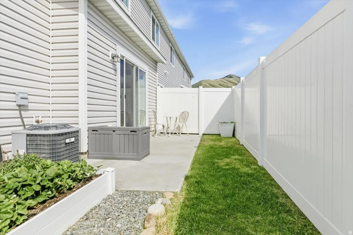 Private outdoor patio featuring concrete paving, a sliding glass door entry, and white vinyl fencing