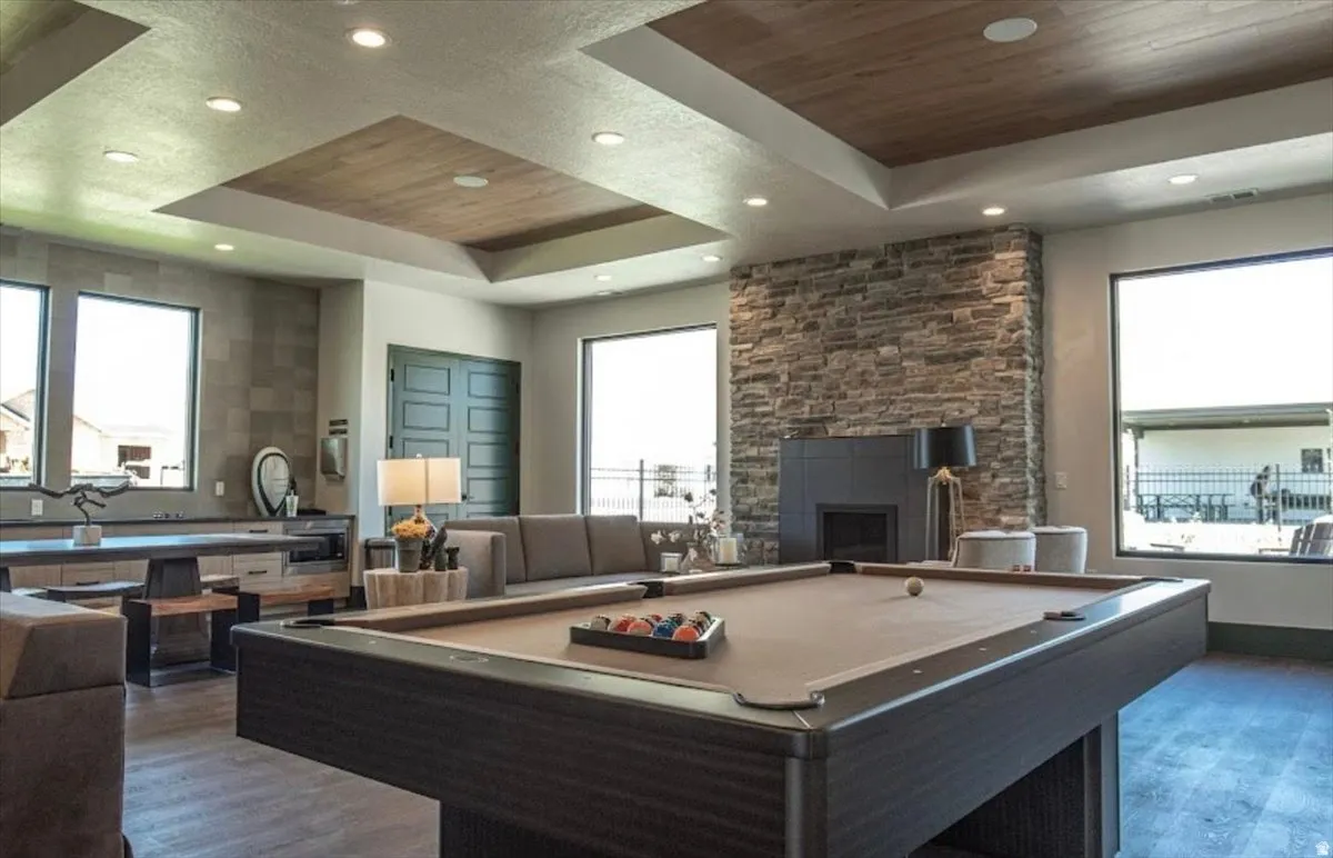 Recreation room featuring a pool table, stone fireplace, wood-finish ceiling accents, built-in cabinetry, and recessed lighting
