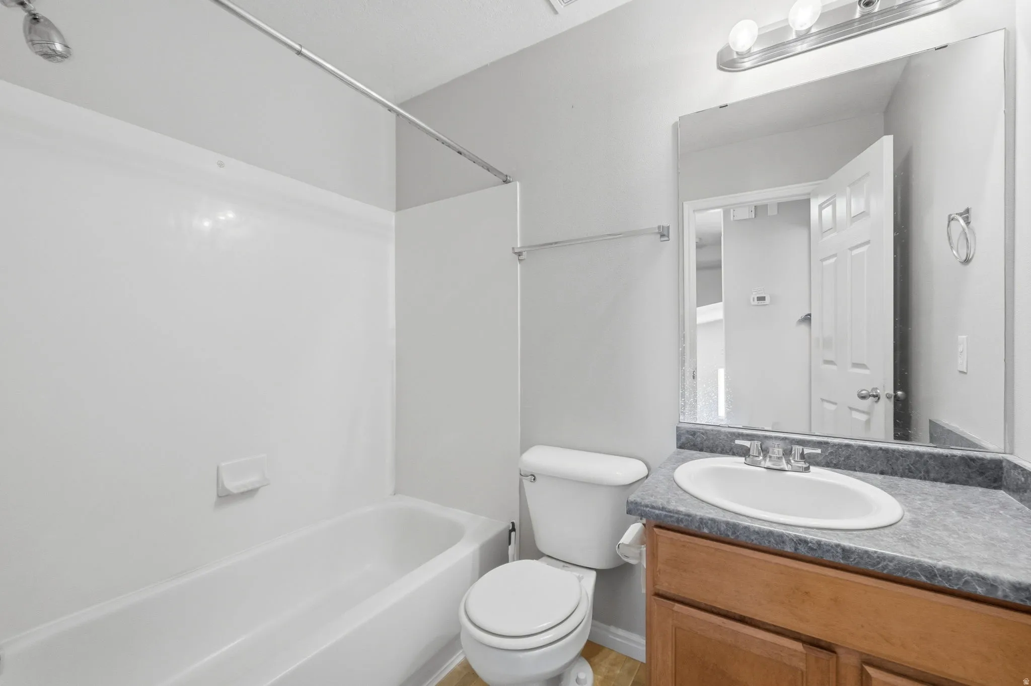 Bathroom featuring a single vanity with a laminate countertop, an undermount sink, and a wood-finish cabinet