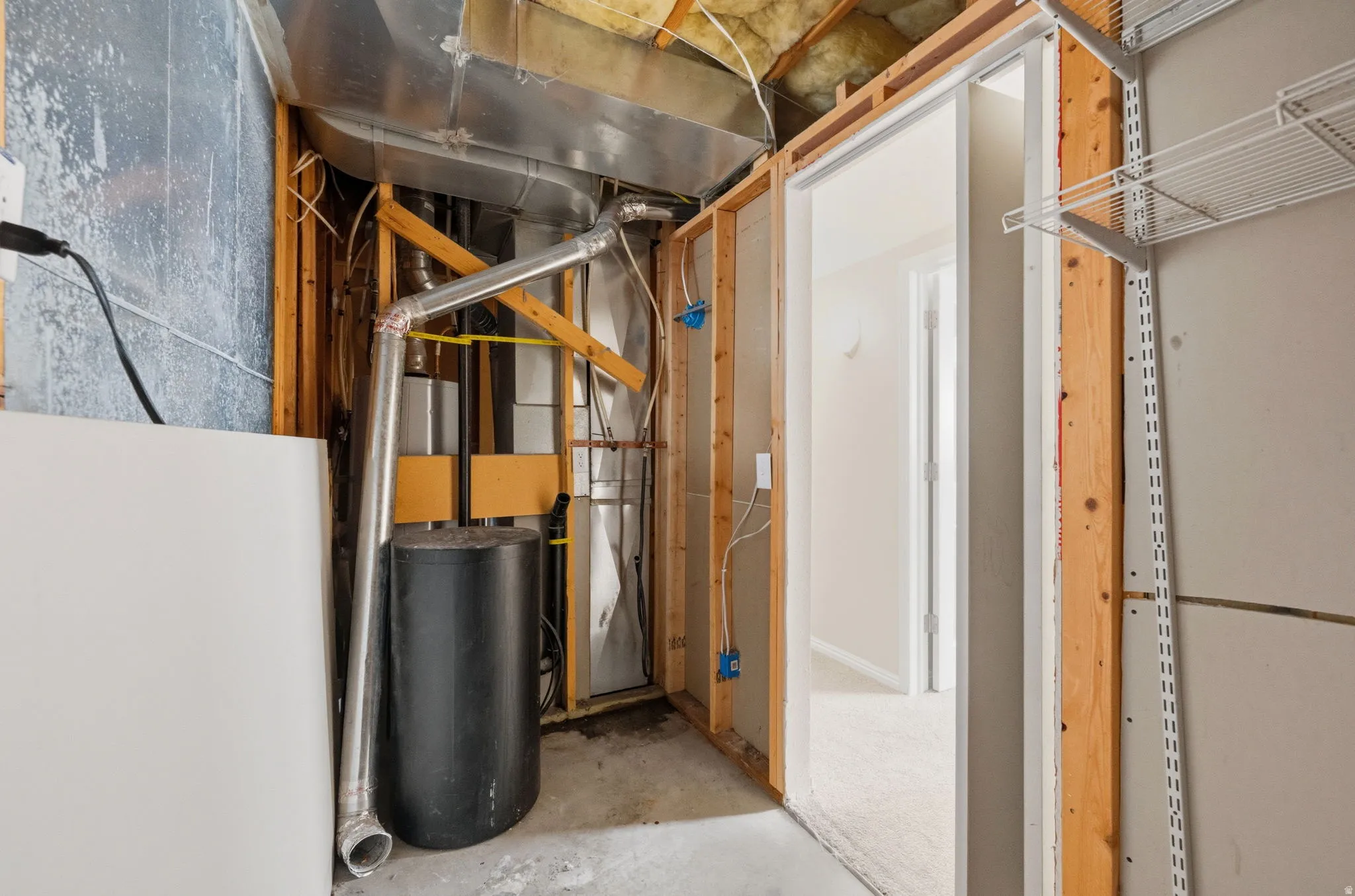 Unfinished utility space featuring exposed wood framing, ductwork, and a water heater