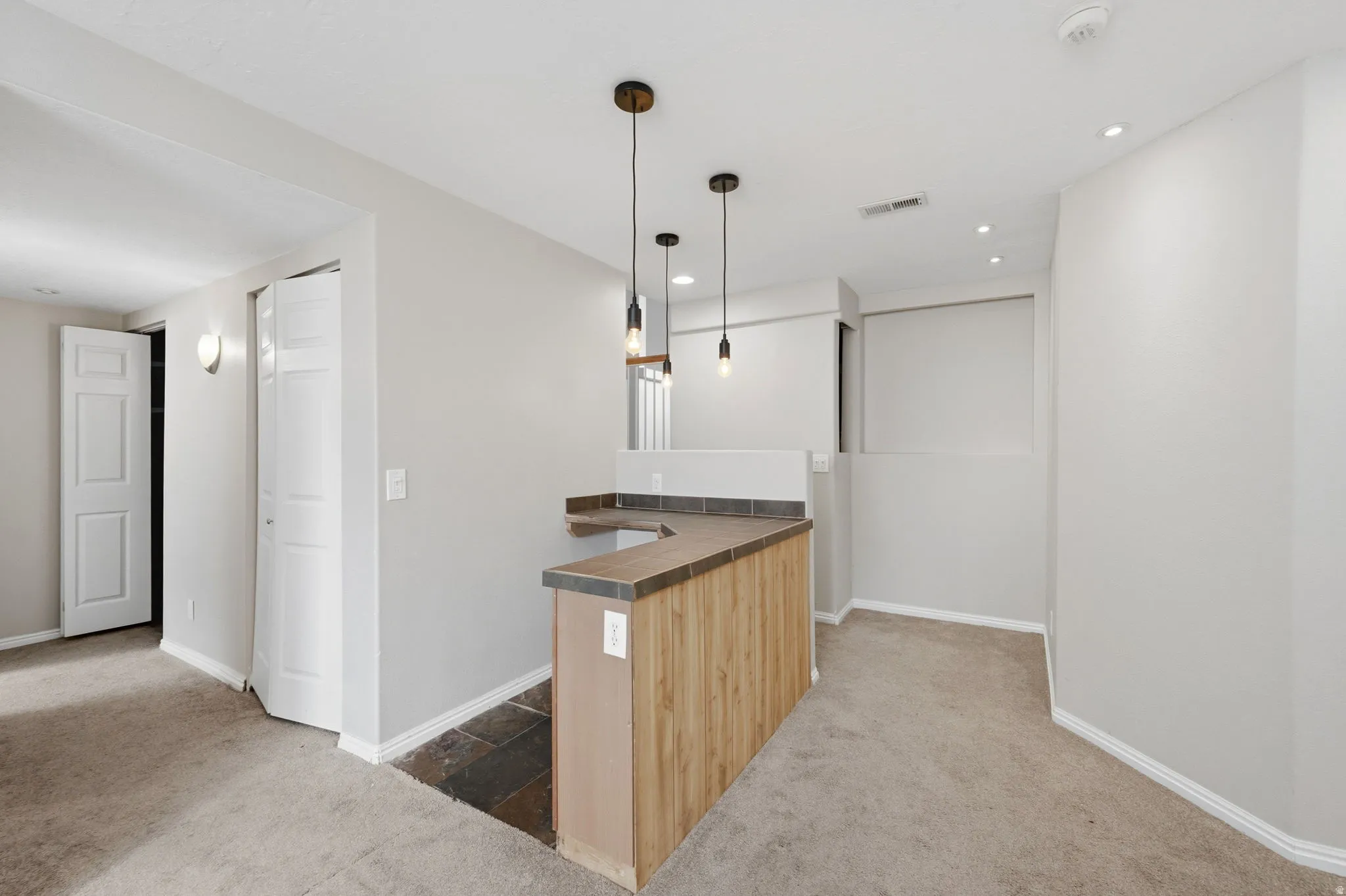 Custom bar area featuring wood-finish paneling, a dark countertop, and three pendant lights