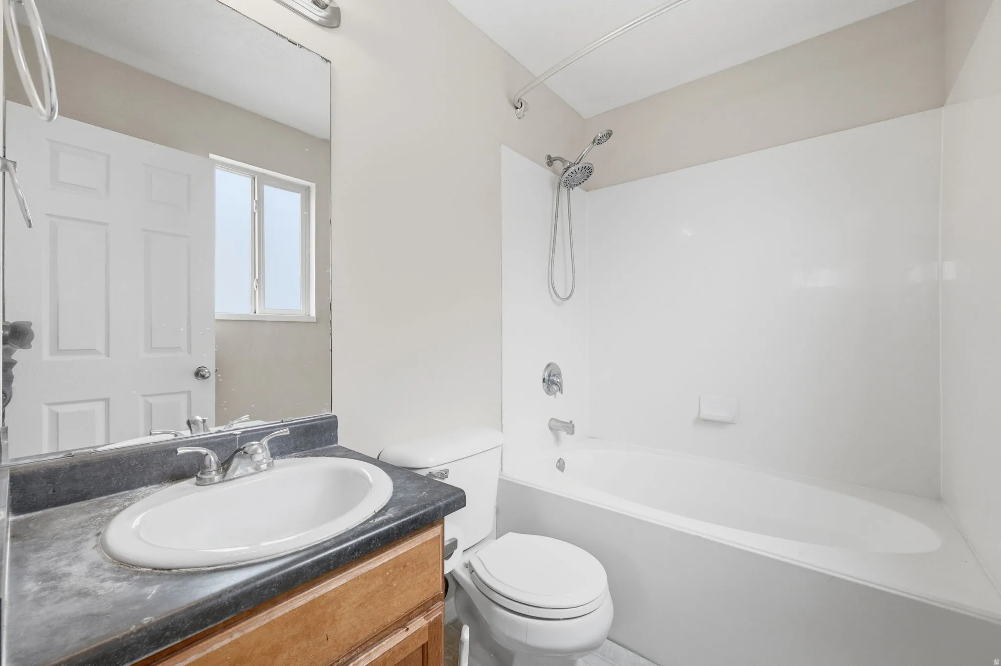 Bathroom featuring a single vanity with wood-finish cabinetry, a built-in sink, and a dark countertop