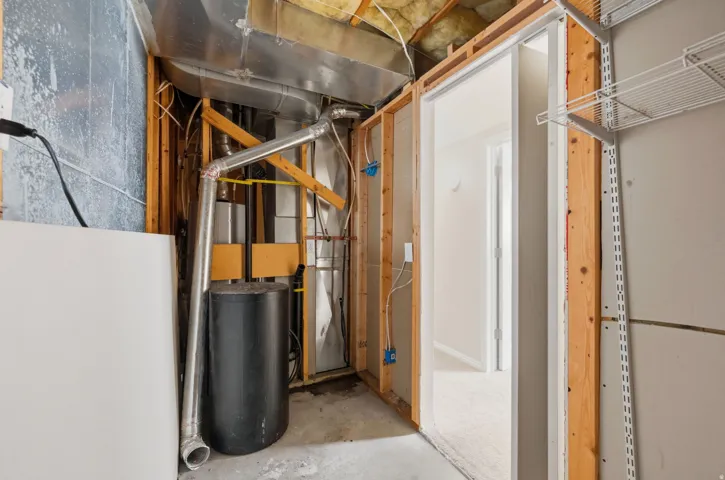 Unfinished utility space featuring exposed wood framing, ductwork, and a water heater