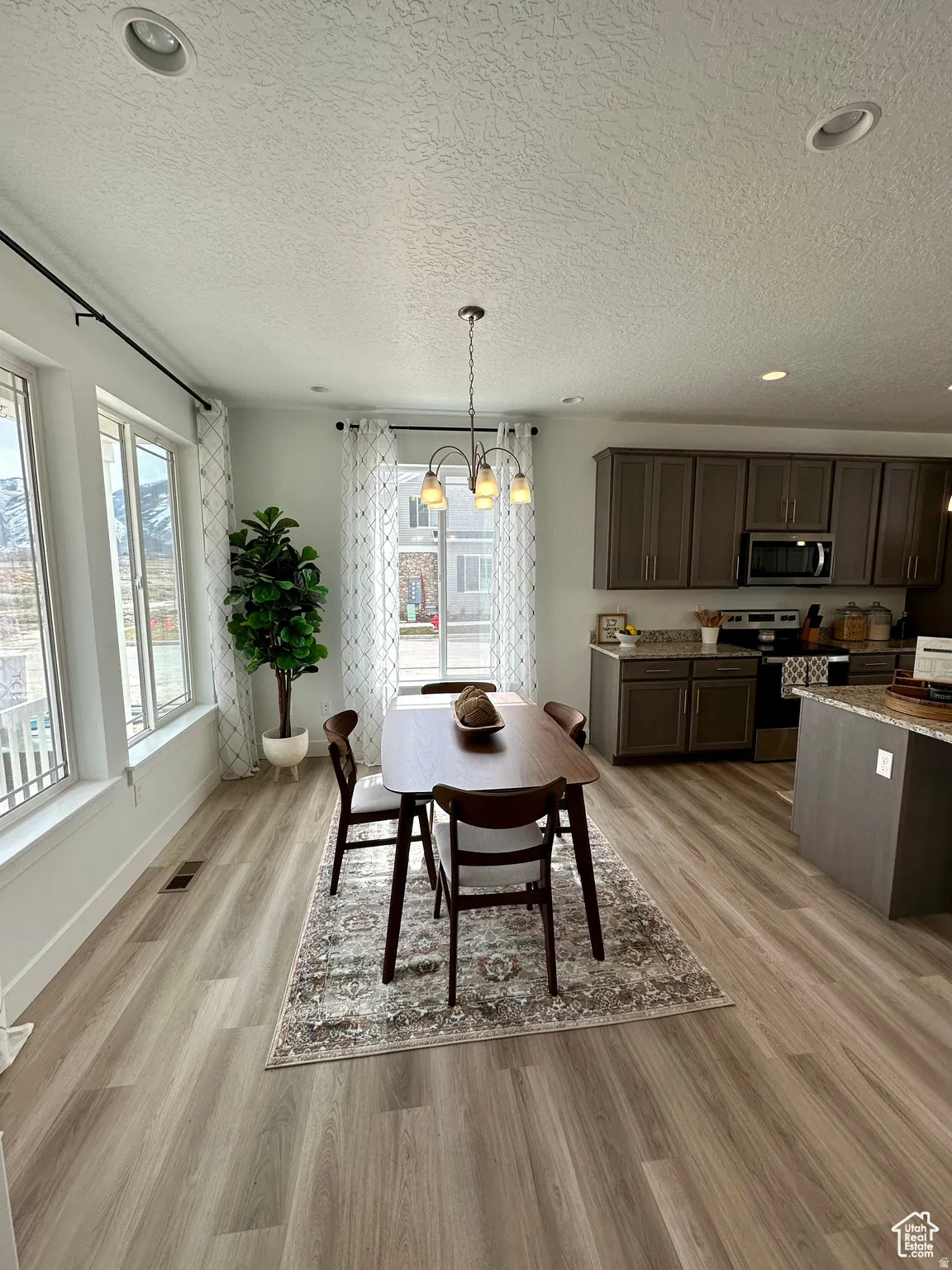 Open-concept living space featuring wood-finish flooring, recessed lighting, and a contemporary chandelier