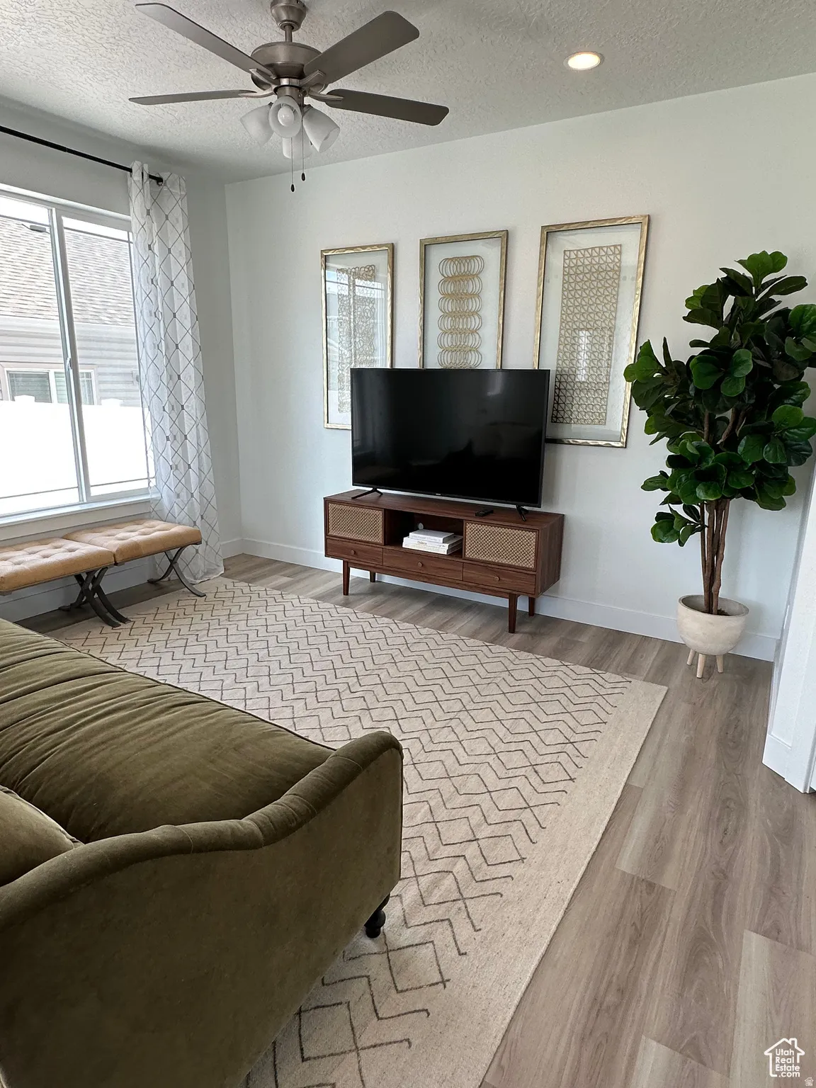 Living area featuring wood-finish flooring, a ceiling fan with integrated lighting, and recessed ceiling lights