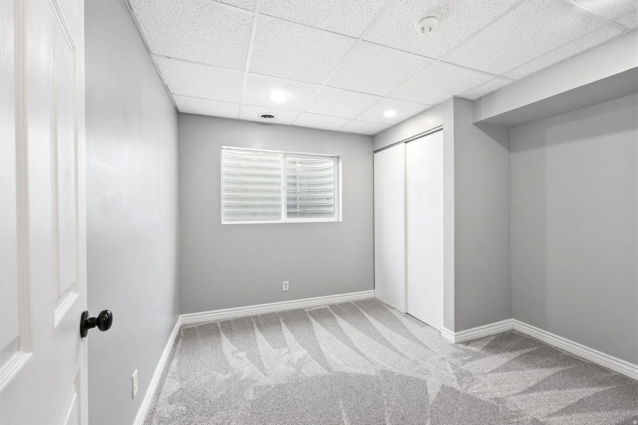 Room featuring light grey walls, white trim, and patterned carpeting
