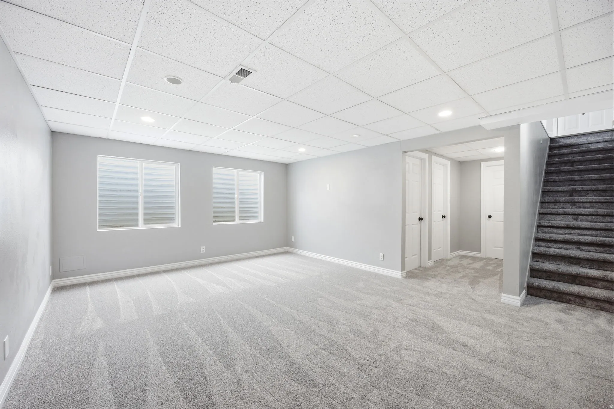 Spacious lower-level room featuring light gray carpeting and neutral wall tones