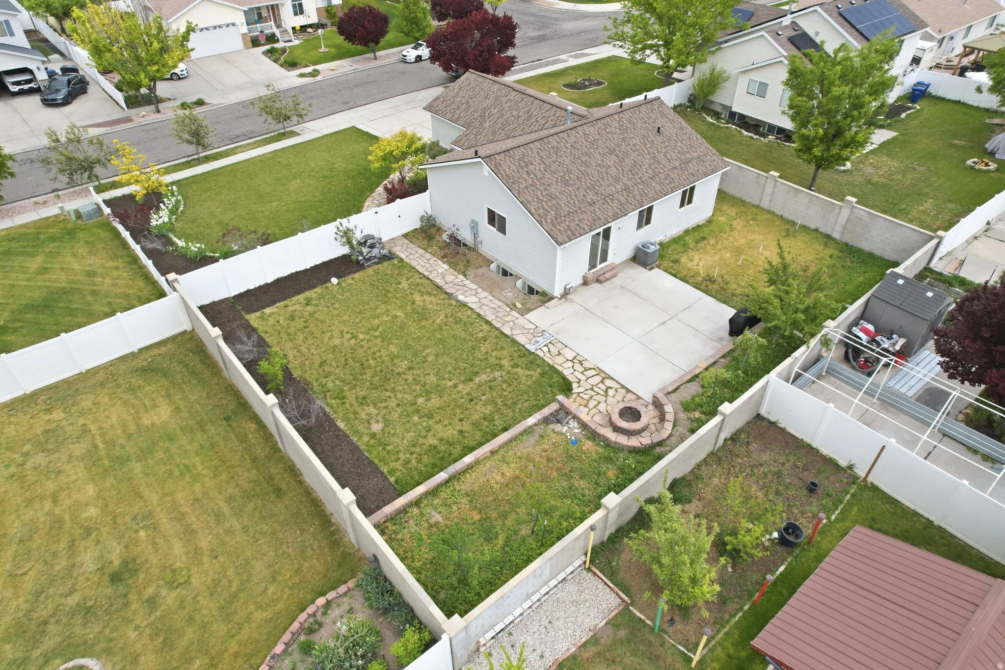 Spacious rear yard featuring a concrete patio, stone pathway, built-in fire pit, and privacy fencing