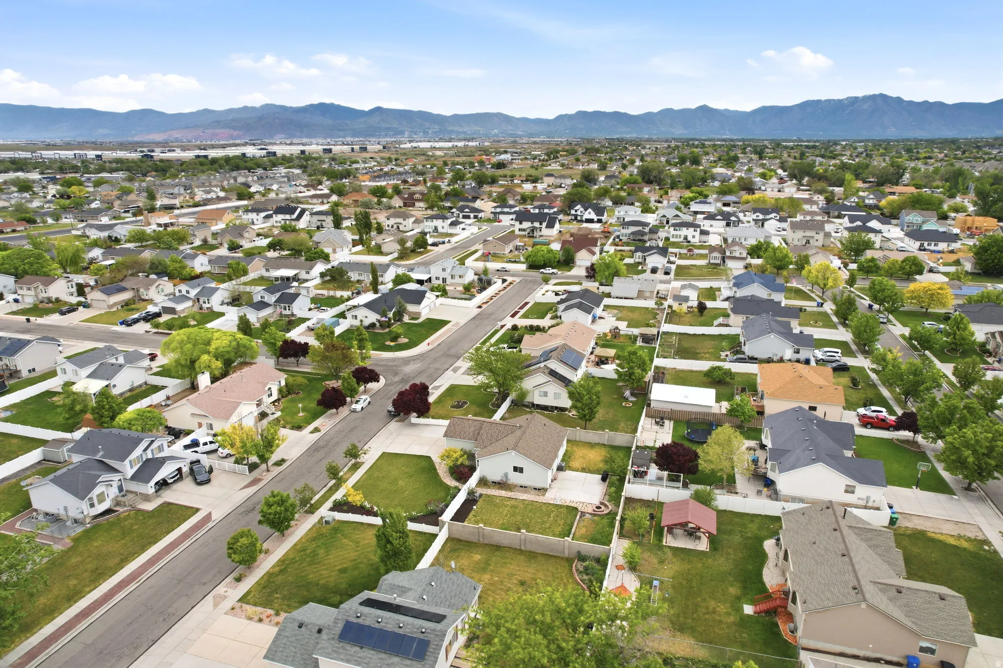 Residential neighborhood featuring a grid-pattern street layout, mature trees, and mountain scenery in the distance