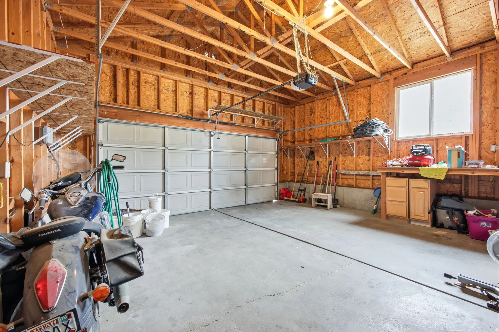 Spacious garage featuring a concrete floor, exposed wooden rafter ceiling, and a large overhead door