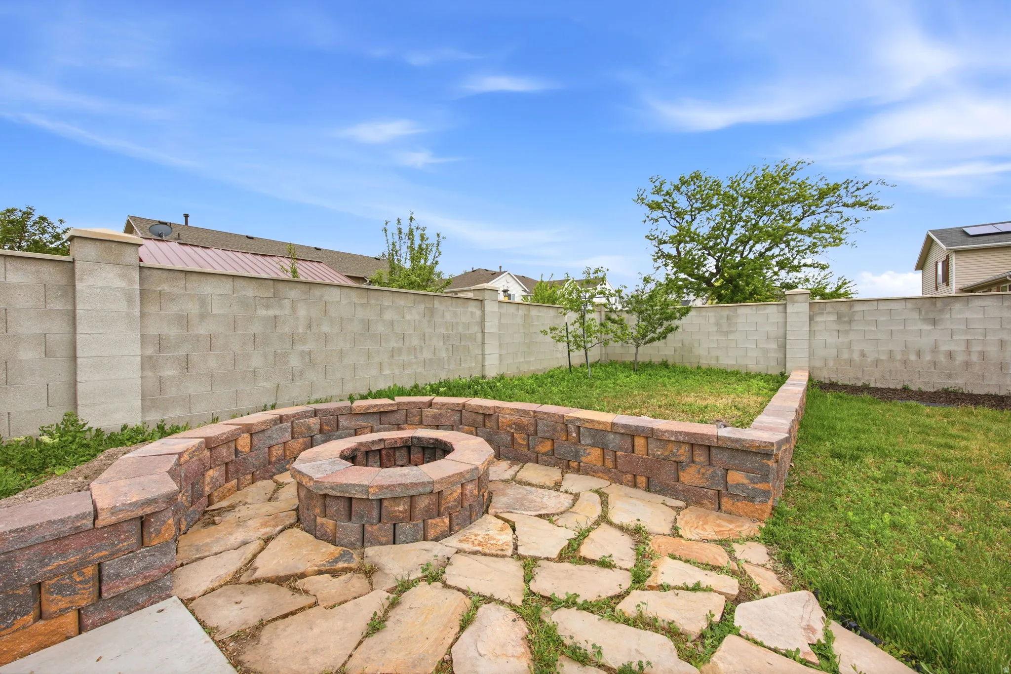 Outdoor living area featuring a stone-paver patio, built-in fire pit, and low retaining walls