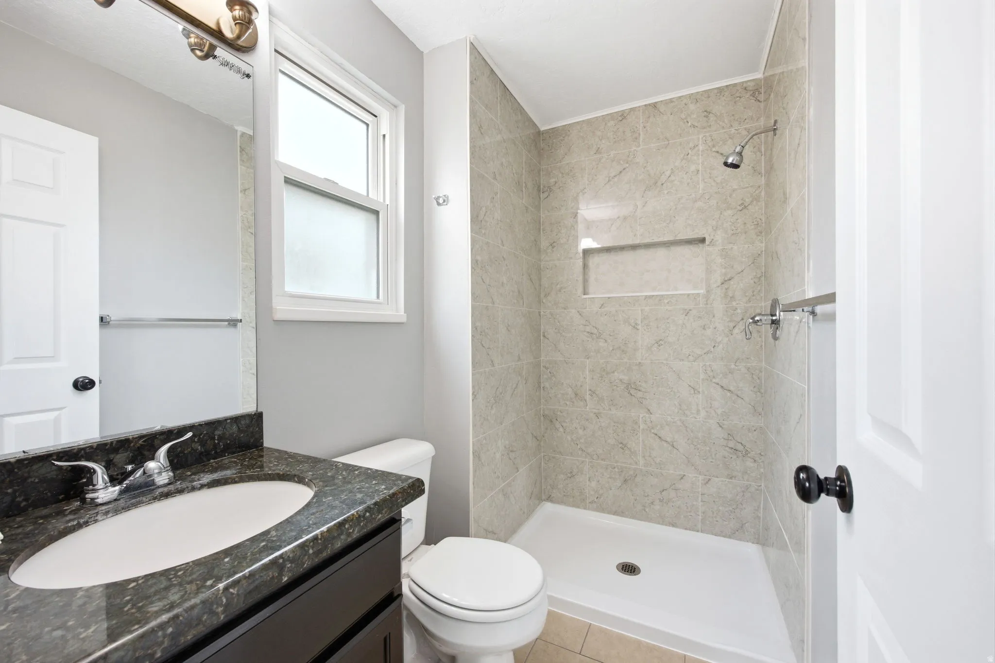 Tiled shower with an integrated niche and a white shower pan