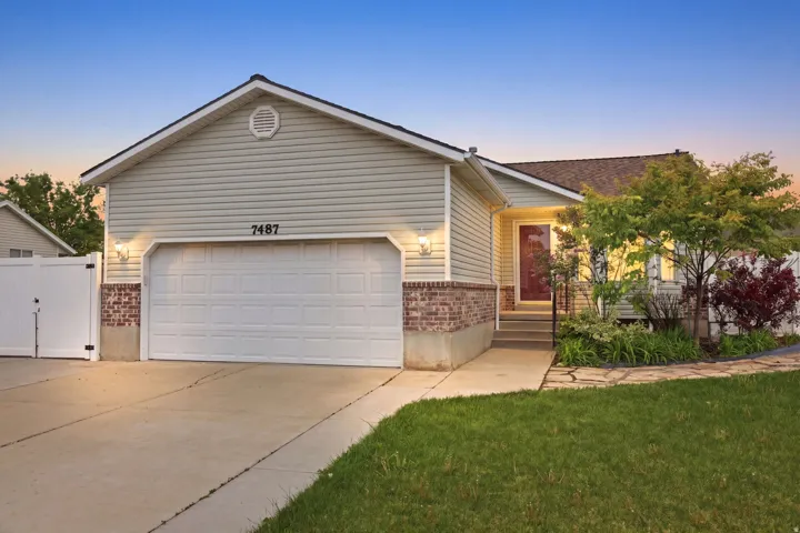 Ranch-style residence featuring light-colored siding, a brick foundation accent, and a front-facing attached garage