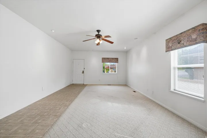 Spacious living area featuring a ceiling fan, recessed lighting, and multiple windows for natural light