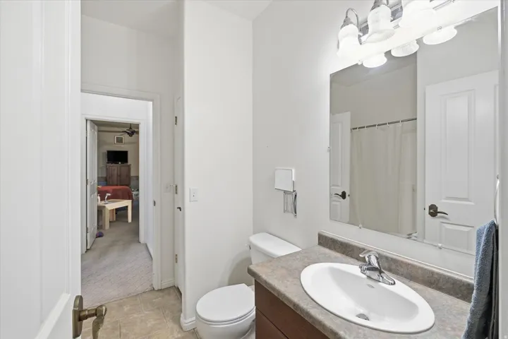 Bathroom featuring a single vanity with an oval sink, a stone-look countertop, and a wood-finish cabinet